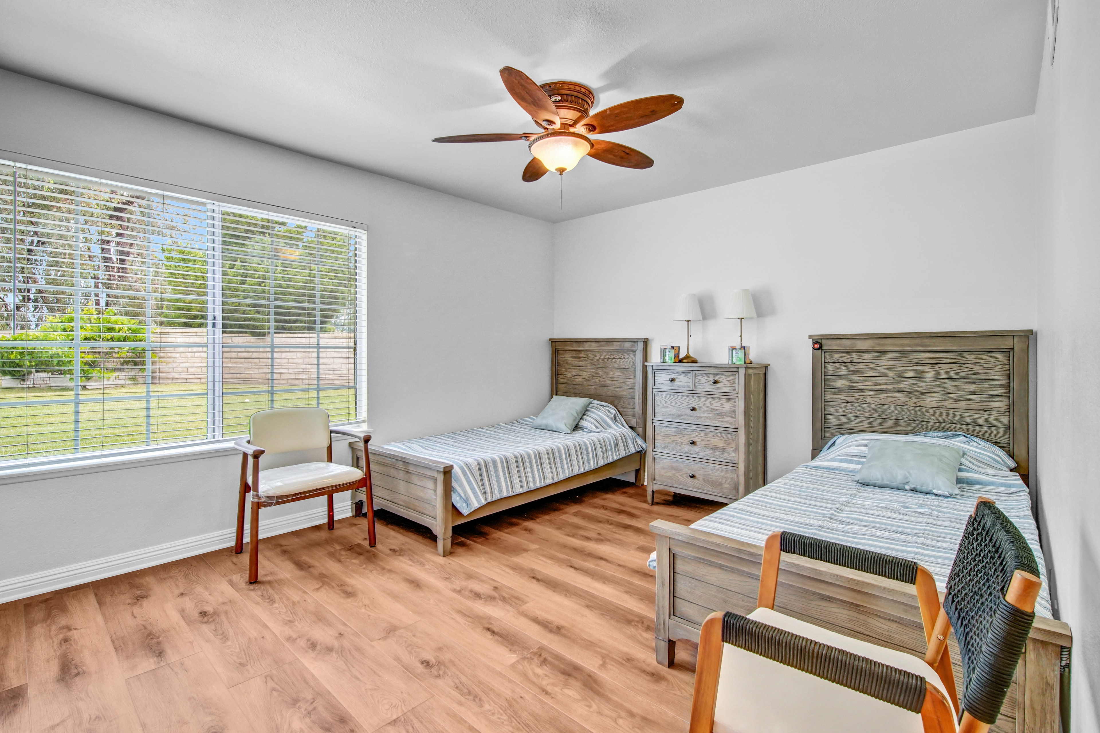 Bright shared bedroom with garden view and ceiling fan