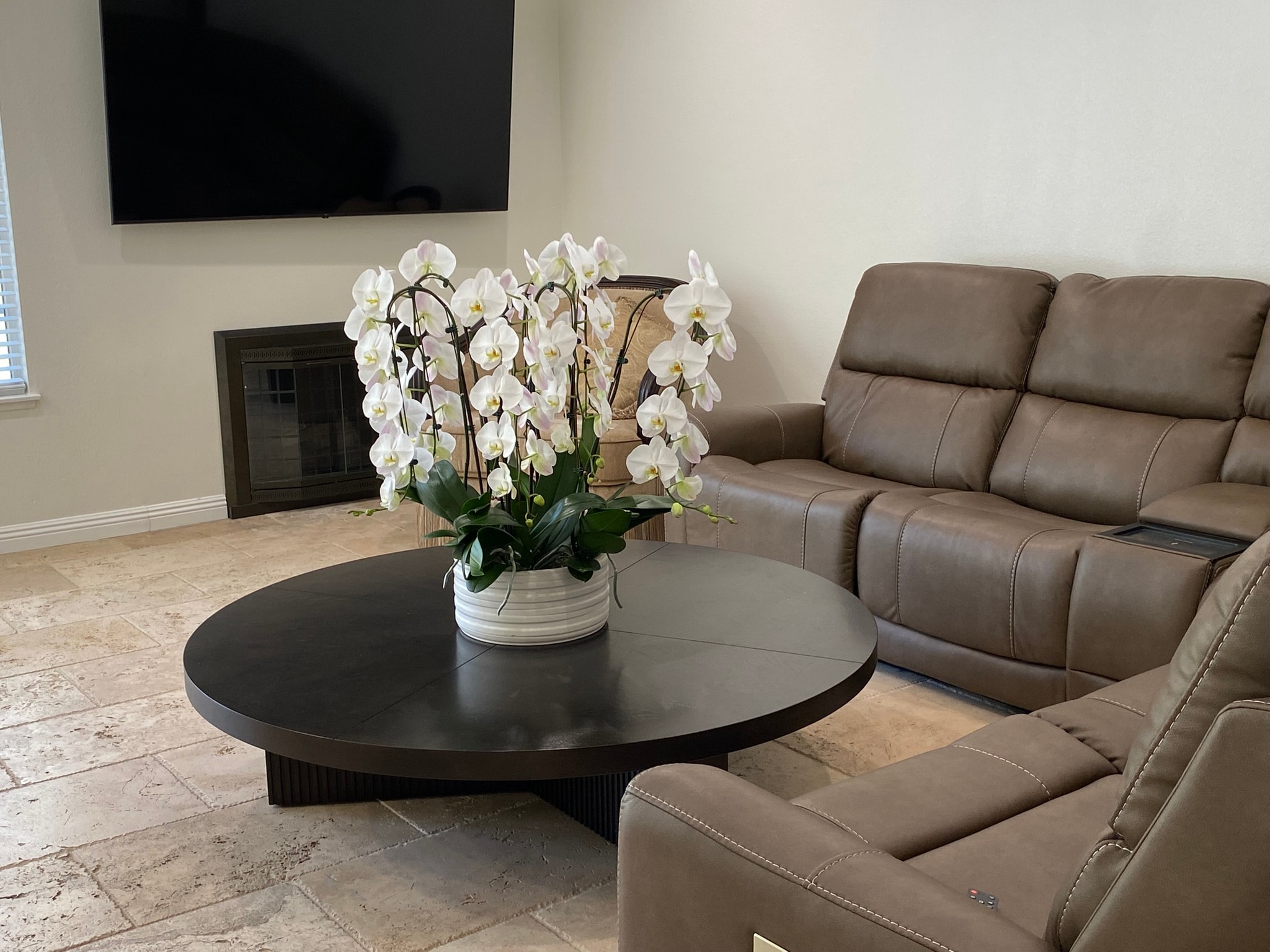 Living room with leather recliners, fireplace, and white orchids